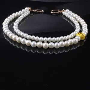Modieuze parelketting met smiley en gouden kreeftsluitingen op een zwart reflecterend vlak