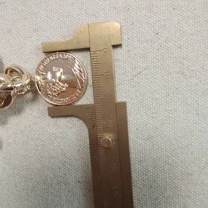 Detail view of 25mm gold queen coin pendant being measured with a caliper