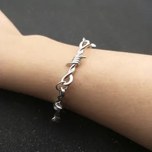 Primer plano de la pulsera de alambre de espino plateado con brillo metálico en la muñeca