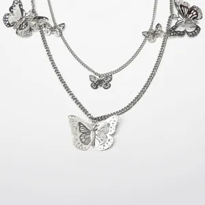Detailed close-up of layered silver chain necklace featuring hollow butterfly pendants