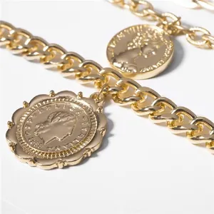 Close-up of golden multi-layer curb chain with embossed coin pendant and portrait detail