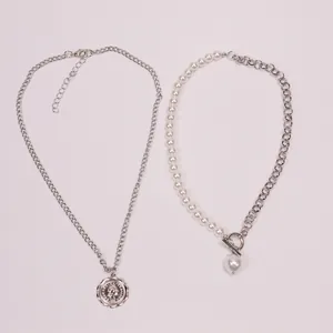 Detail of baroque pearl choker and coin pendant necklace with toggle clasp on white background