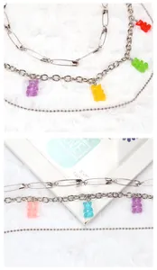 Close-up of layered silver chains with colorful gummy bear pendants and safety pin accents