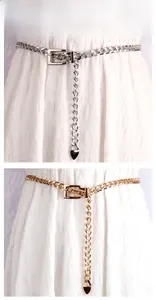 Détail de ceintures chaîne en métal argenté et doré avec pendentifs cœur sur robe