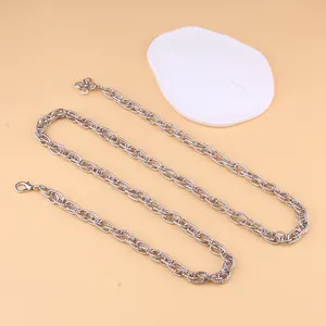 Detail van zilveren gedraaide schakelketting met karabijnsluiting en klavertje vier