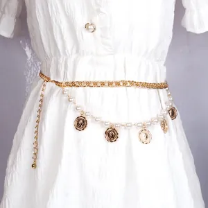 Gouden lichaamsketting met munt hangers en immitatieparels over een witte jurk