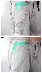Details von silbernen Hosenketten mit Schmetterlingsanhängern auf Denim-Shorts