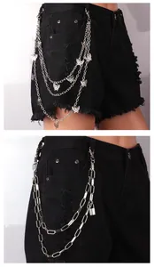 Detail view of multi-layer silver butterfly chain and padlock charm on black denim