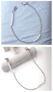 Detail of retro U-shaped silver metal chain with imitation pearls and lobster clasps