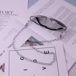 Detail of grey acrylic link chain and pilot sunglasses on a stylish paper background
