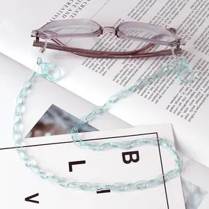 Close-up of light blue acrylic glasses chain with metal lobster clasp on purple frame