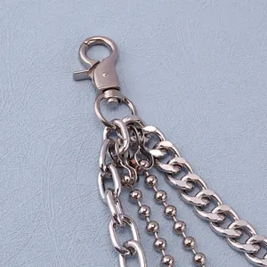 Detalle de cadena de pantalón multicapa en metal plateado con mosquetón resistente