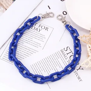 Detail van grove helderblauwe acryl broekketting met zilveren karabijnsluitingen als accessoire