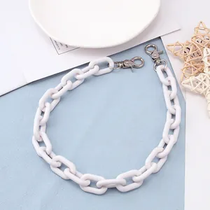 Detail van witte acrylketting met zilveren karabijnsluitingen voor jeans of tassen