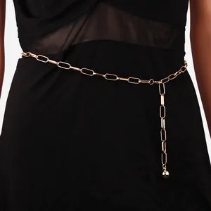 Gros plan détaillé d'une chaîne de taille dorée avec pendentif boule sur robe noire