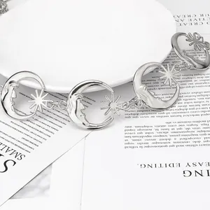 Détail d'une chaîne de taille argentée avec pendentifs lune et étoile sur présentoir