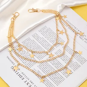 Detail of a multi-layer gold star body chain with lobster clasps on white satin fabric