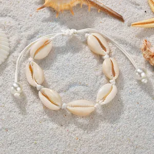 Bracelet tressé en coquillages pour femme sur sable blanc avec décorations d'étoiles de mer
