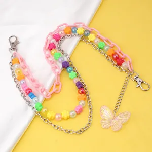 Macro detail of layered pink acrylic chains and a colorful flower bead body chain