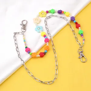 Detail of colorful flower beads and pink butterfly pendant on a layered metal waist chain