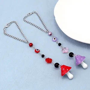 Detail of beaded evil eye and mushroom charms with silver chains and lobster clasps