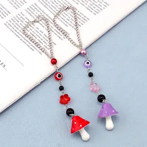 Detail of mushroom and evil eye beads charm on a metal chain with floral accents