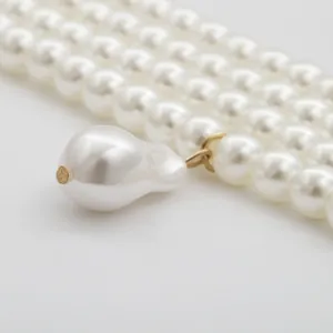 Elegant four-layer pearl necklace featuring a large baroque pearl pendant on light background