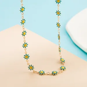 Détail du collier doré orné de plusieurs breloques marguerites en émail bleu et jaune