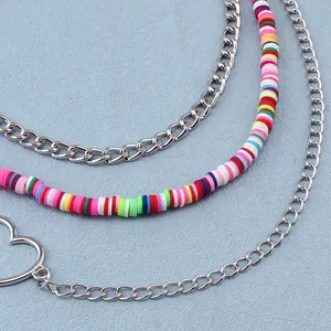Detail of multi-layered silver chain featuring colorful heishi beads and hollow heart pendant