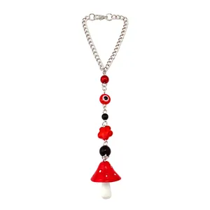 Detail of red evil eye bead chain with a mushroom charm and silver metal lobster clasp