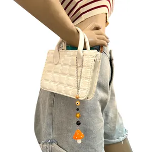 Detalle de colgantes de resina de setas y ojo turco en un bolso acolchado blanco