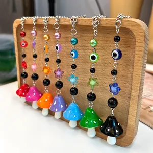 Detalle de colgantes de seta de resina colorida y ojo turco en soporte de madera