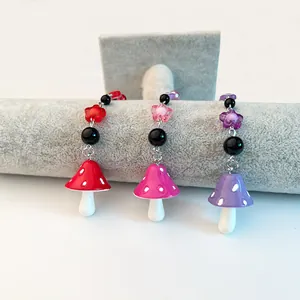Détail de breloques champignons rouges, roses et violets avec perles fleurs sur support