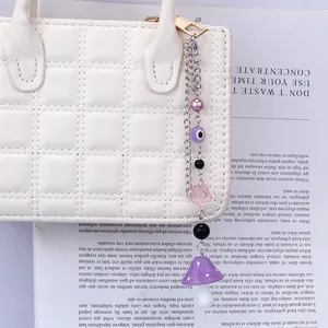Détail d'un pendentif bohème œil protecteur et champignon violet sur un sac blanc
