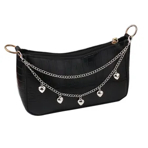 Detail of black crocodile texture baguette bag with silver heart chain charms