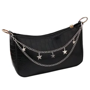 Detail of black crocodile texture handbag with star charms and silver chain straps