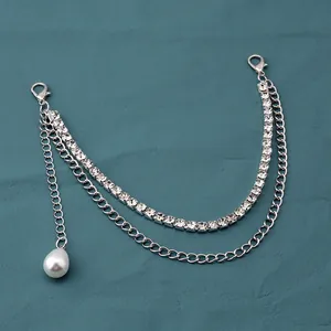 Detail of silver layered handbag chain featuring sparkling rhinestones and a pearl pendant