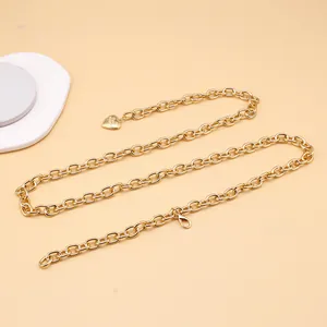 Detail of a gold link waist chain featuring a heart pendant and secure lobster clasp