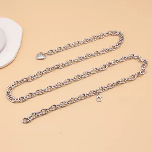 Macro view of silver cross chain waist belt featuring a vintage heart pendant and lobster clasp