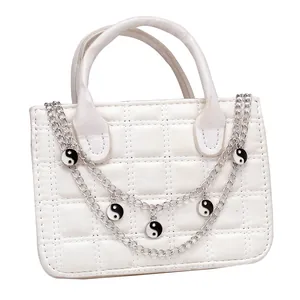 Detail der weißen Stepphandtasche mit Silberkette und Yin-Yang-Anhängern in Schwarz-Weiß