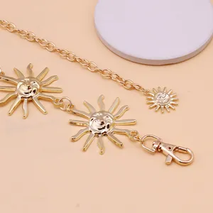 Detailed macro view of golden metal chain belt featuring embossed sunflower smiley face charms
