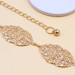 Macro detail of golden metal hollow leaves and ball pendant on a stylish waist chain