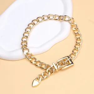 Detail of gold chain necklace with buckle fastener and heart pendant on ceramic tray