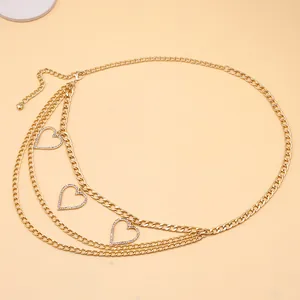 Détail de la chaîne de taille dorée multicouche avec pendentifs en forme de cœur et strass