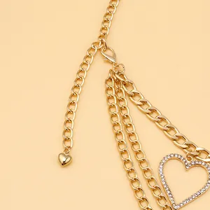 Détail d'une chaîne de corps dorée multicouche avec pendentif cœur et strass brillants