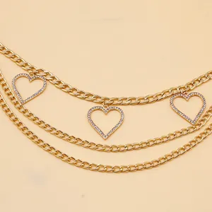 Détail d'une chaîne de taille dorée à trois couches avec pendentifs cœur sertis de strass