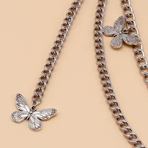 Macro detail of silver vintage punk chain with engraved butterfly pendant charms