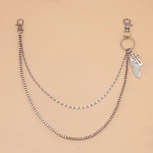 Détail d'une chaîne de pantalon double en métal argenté avec pendentifs plume et croix