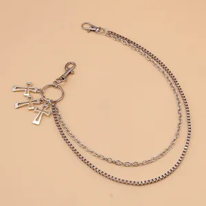 Détail d'une chaîne de pantalon double couche argentée avec pendentifs croix et mousquetons