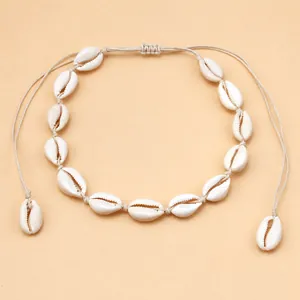 Detail of adjustable bohemian cowrie shell necklace with natural white shells on woven cord